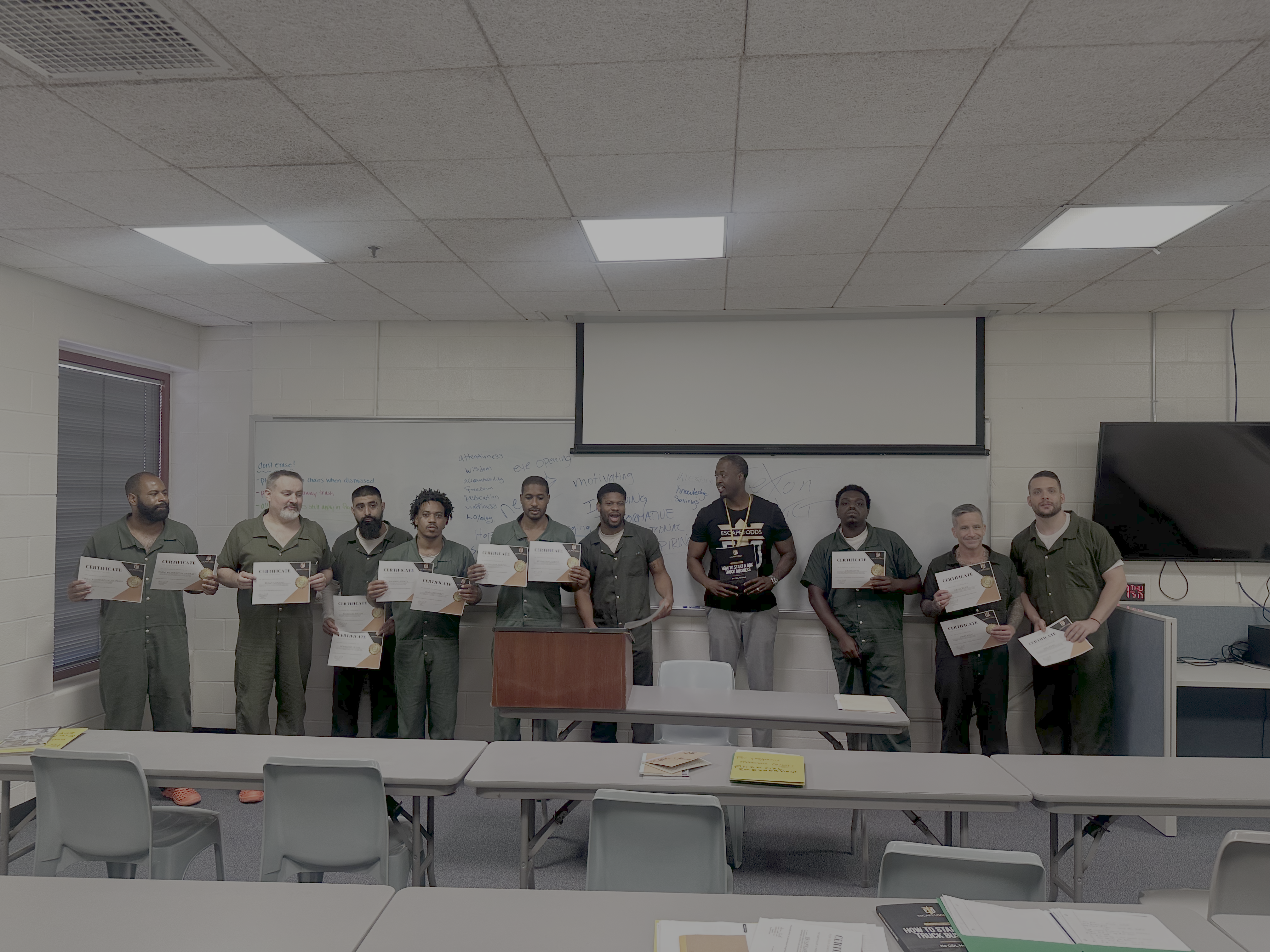 Aaron standing with men in green holding certificates